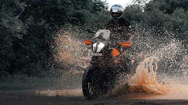 offroad biker riding ktm motorbike through mud puddle spraying