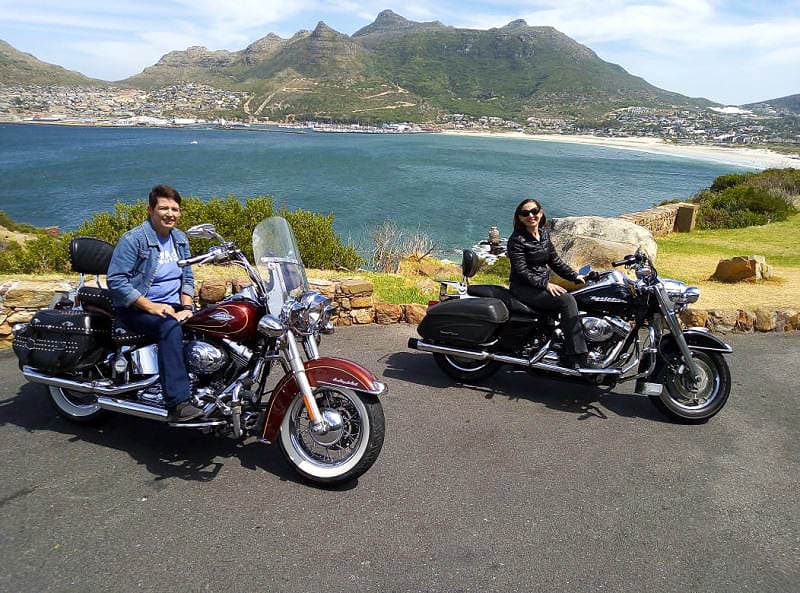 Harley Davidson Rentals Man & Woman Sitting On Harleys With Hout Bay View